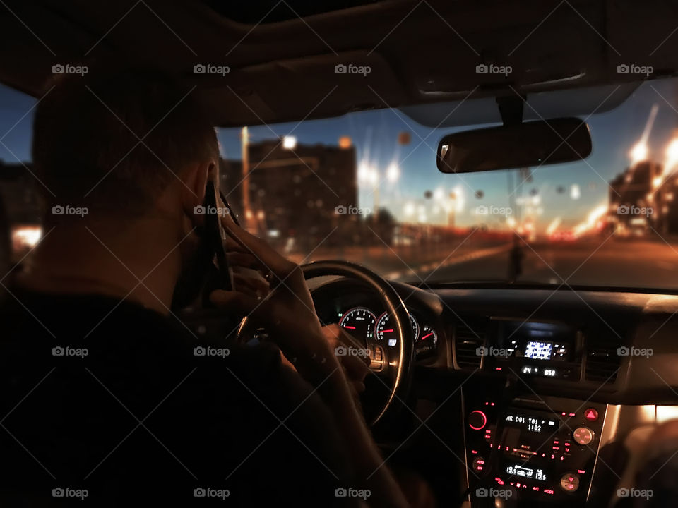 Driving a car and using mobile phone on the city road at night 