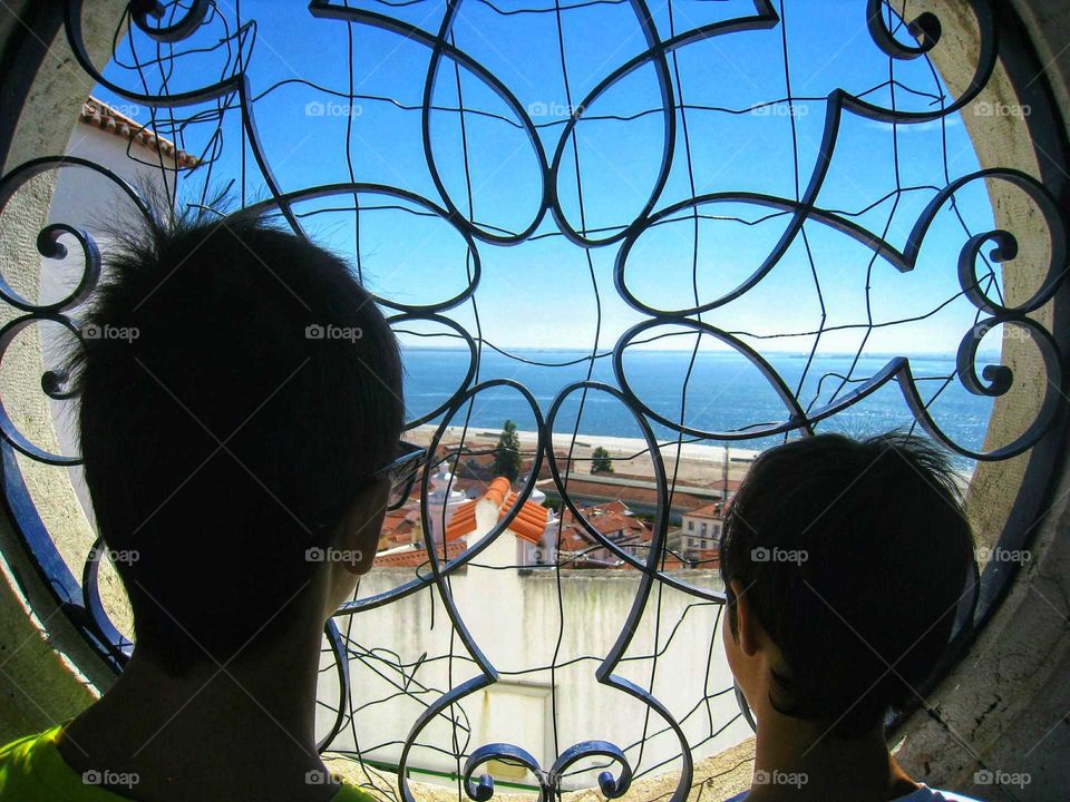 Miradouro de Santa Luzia. Two young boys looking through the window of Santa Luzia's Viewpoint, Lisbon, Portugal