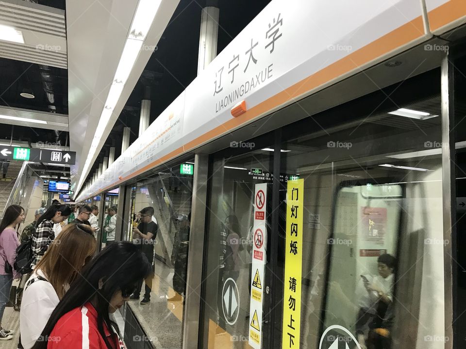 Subway train station in China with people waiting and standing on platform