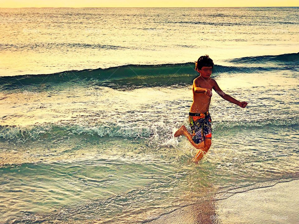 Happy boy playing in the ocean.