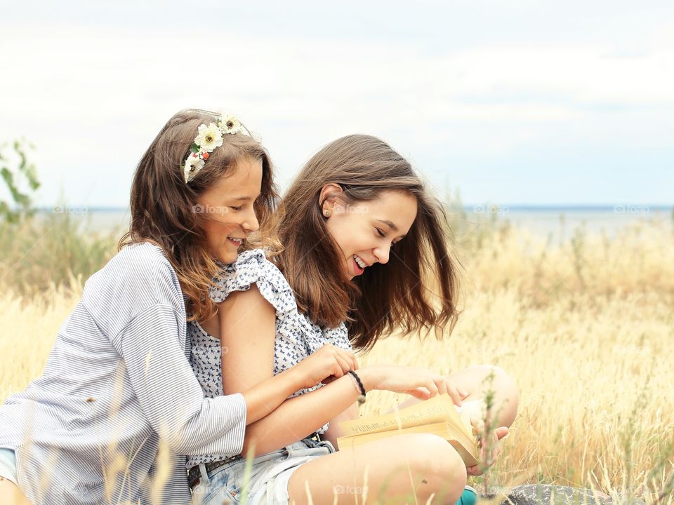 Two girls reading a book and laughing 