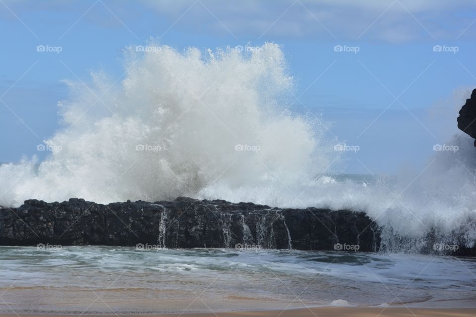 Kauai Water Spray. Water bursting over a rock on a beach in Kauai, Hawaii