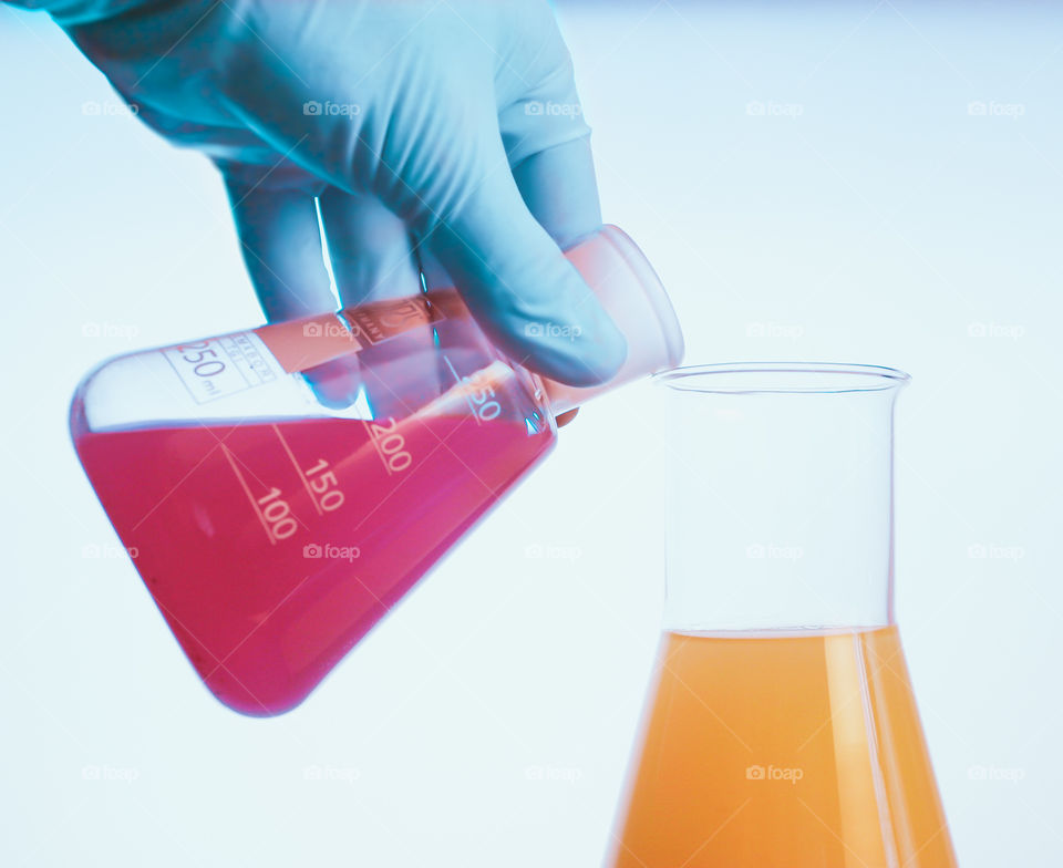 Woman using chemistry and science equipment filled with fluid