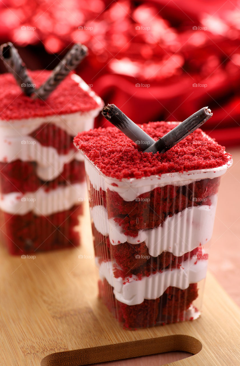 Red cake mousse with white cream in a plastic cup