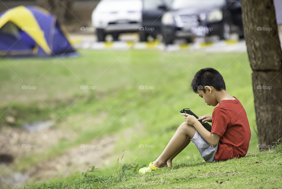 Asian Boys play telephone on the lawn Background blurry image of the car and tent