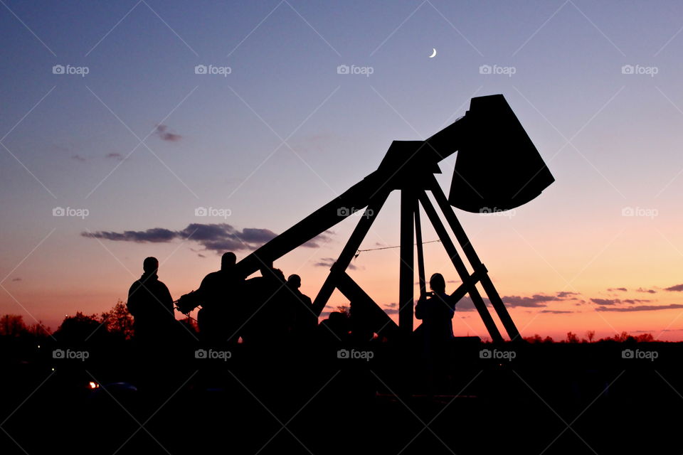 Silhouette of a trebuchet in the sunset