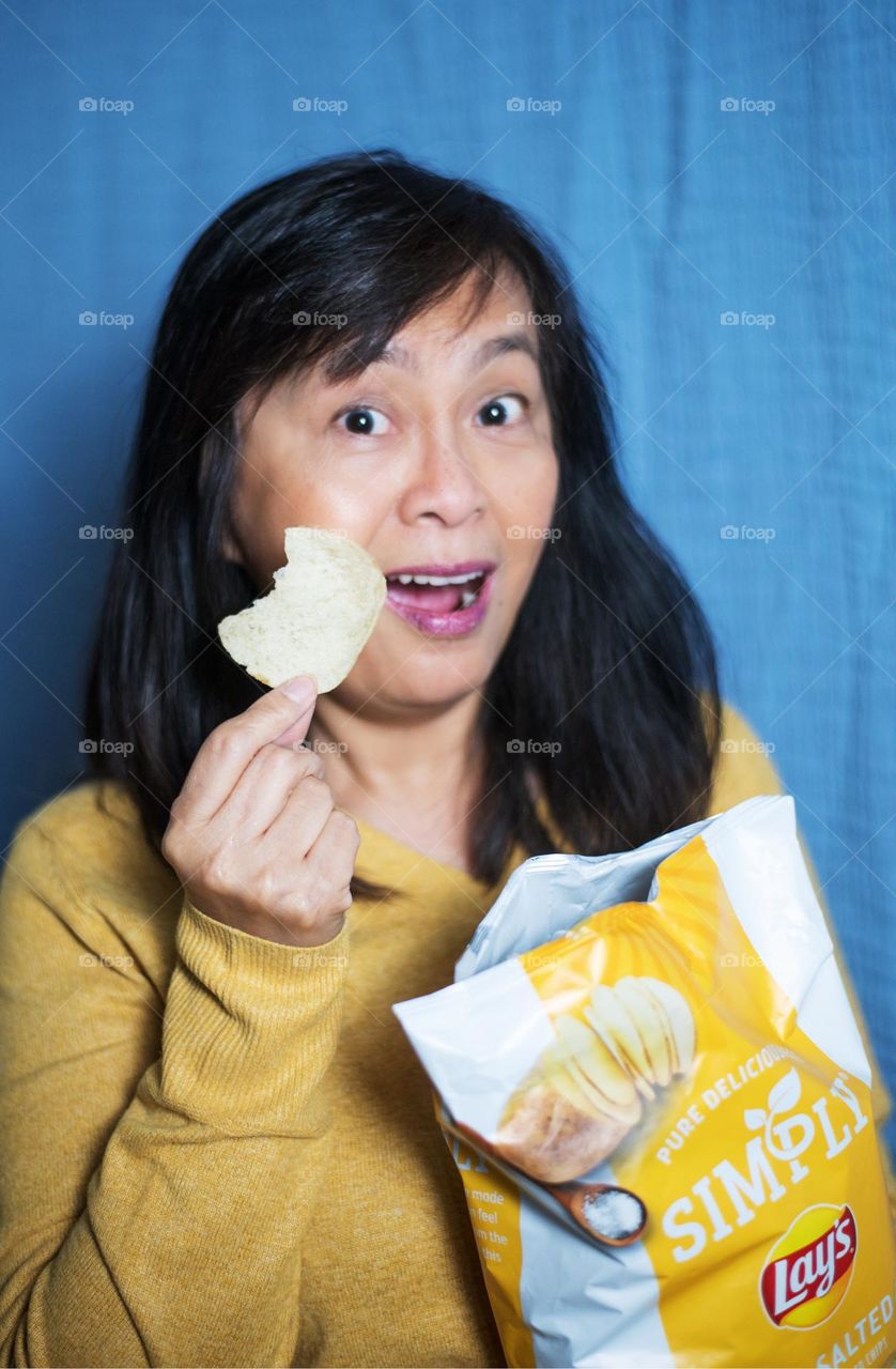 Portrait of a woman eating potato chips 