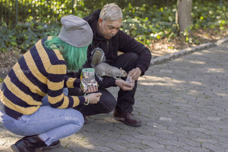 Feeding a squirrel in the park alternative girl and old man