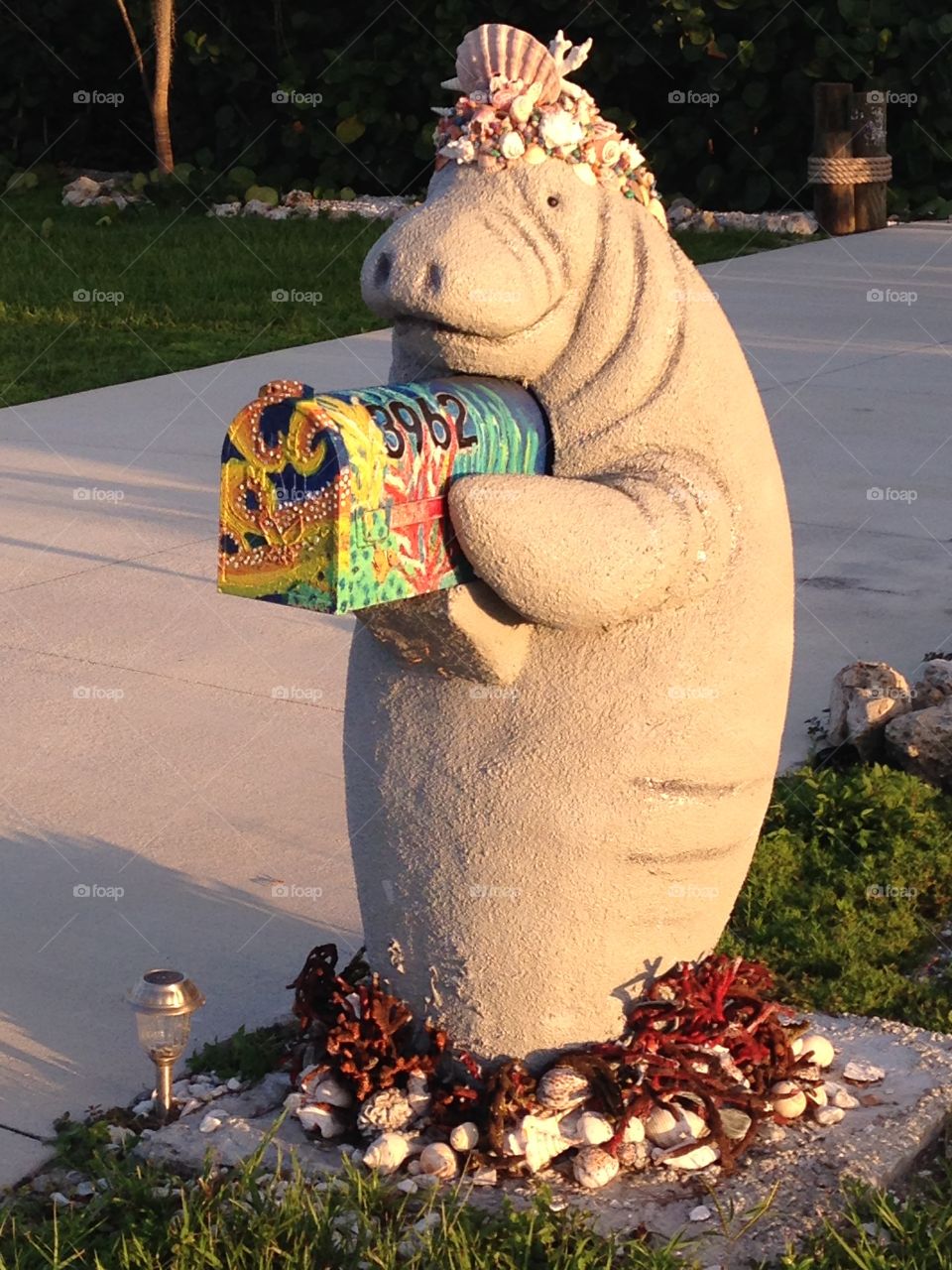 Princess manatee statue holding colorful mailbox