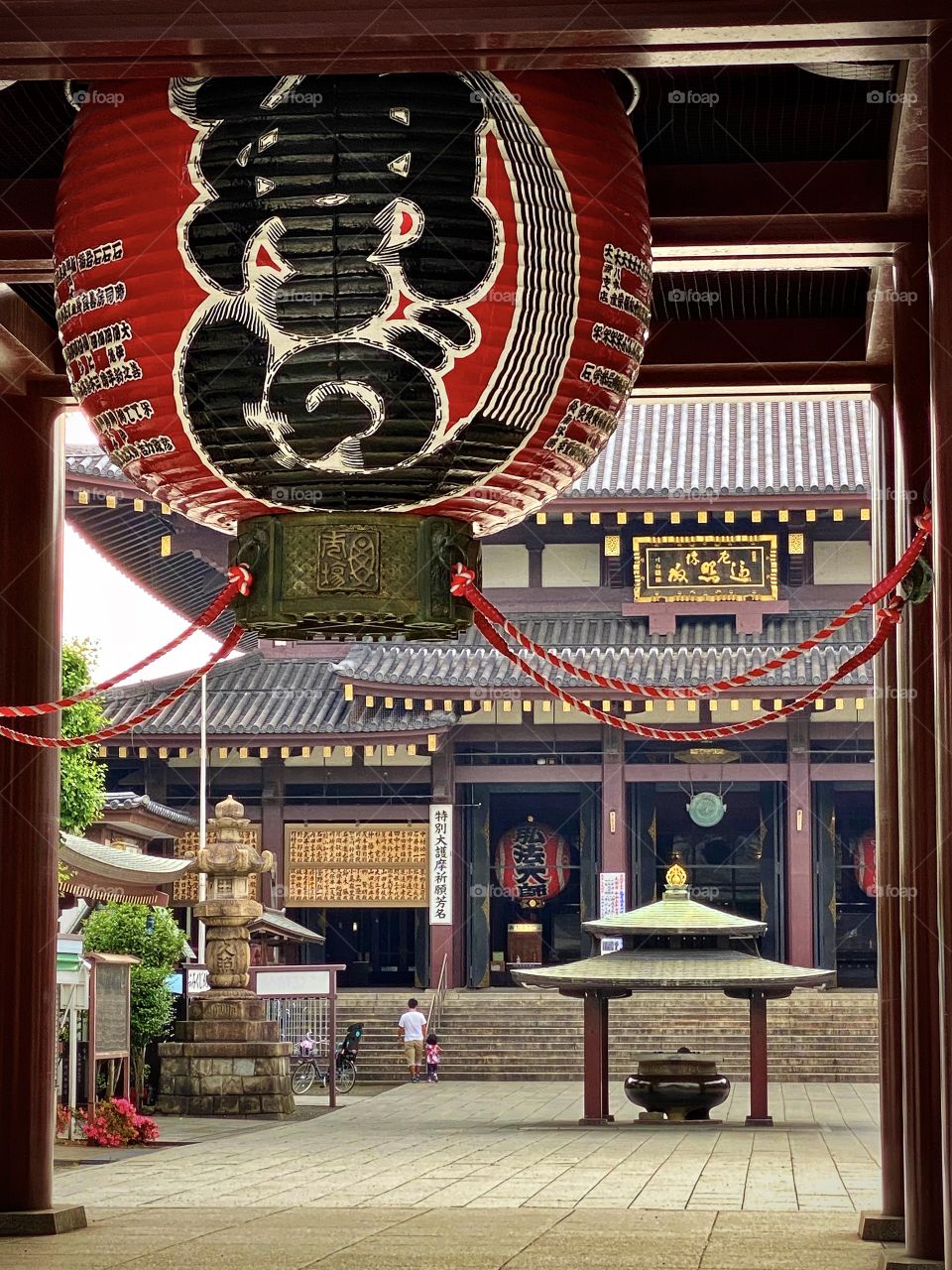 Huge red lantern and looking through main gates to Buddhist temple, dad and daughter walking up steps to the temple 