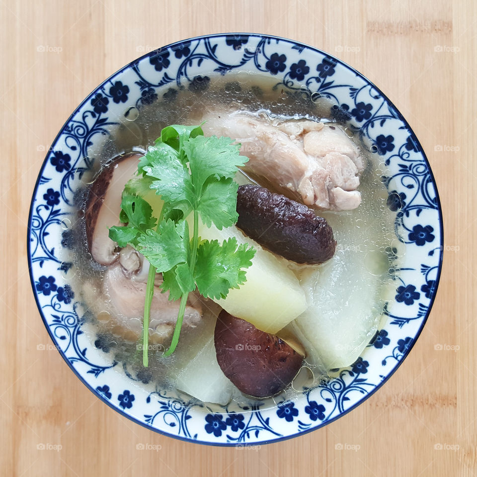 Traditional Chicken and wax gourd soup with pickled lime, serving with coriander leaf on top in china blue and white porcelain - top view