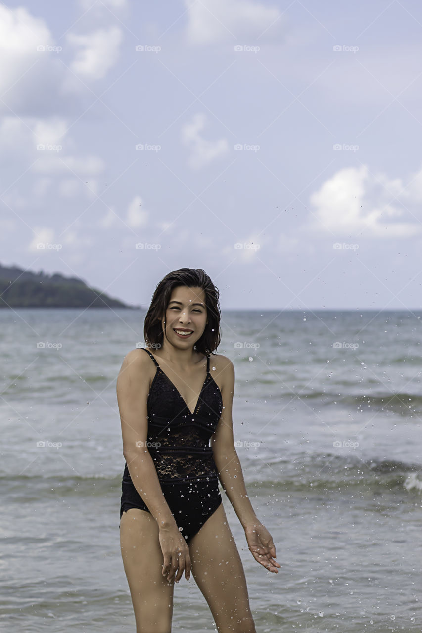 Portrait of Asian woman wearing a swimsuit background sea and sky