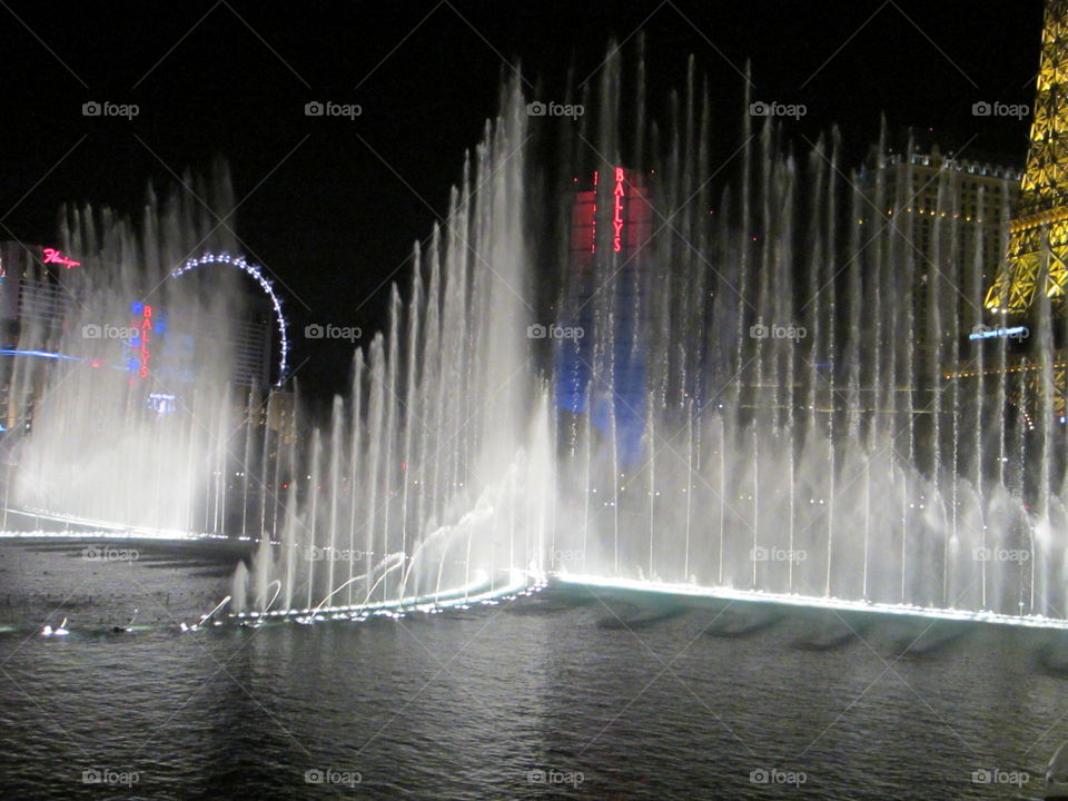 Water and Light Dancing Fountains Show outside Bellagio Hotel and Casino, Las Vegas, Nevada. Illuminated Night View of The Strip behind Fountains.