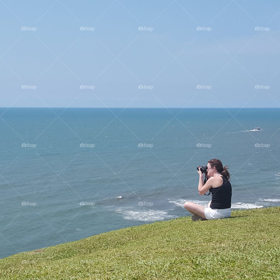 Young woman taking photograph of sea