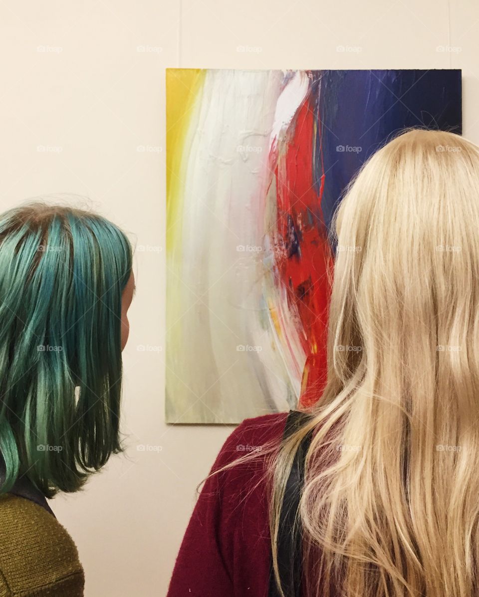 Two girls with green and white hair looking at multicolored artwork