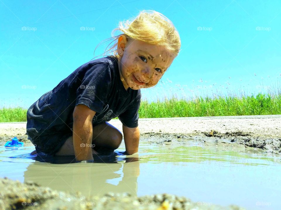 a little girl playing in the mud in the sun's reflection just off of the Gulf Coast near Bridge City Texas United States of America 2018