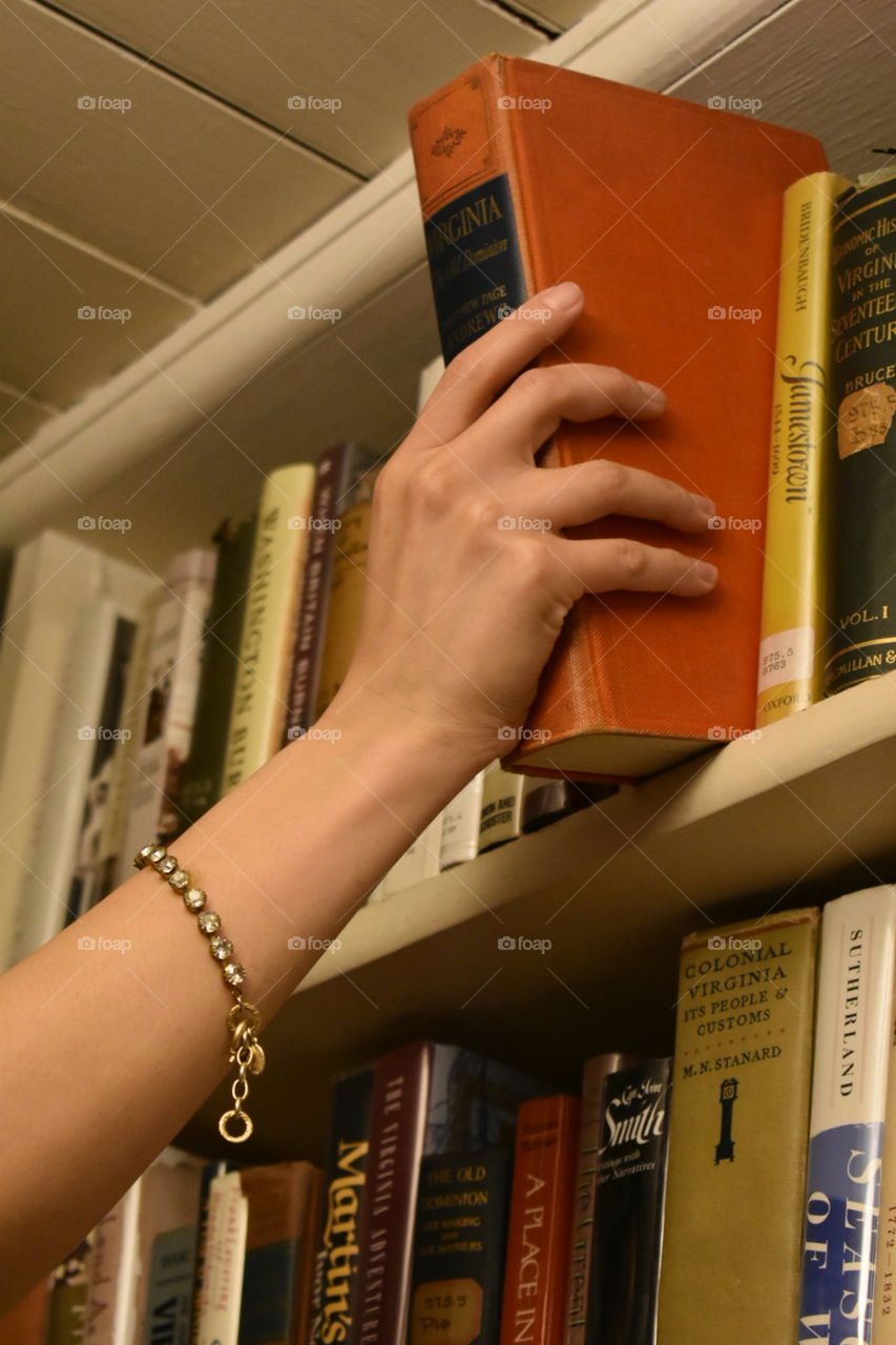 woman taking book from shelf