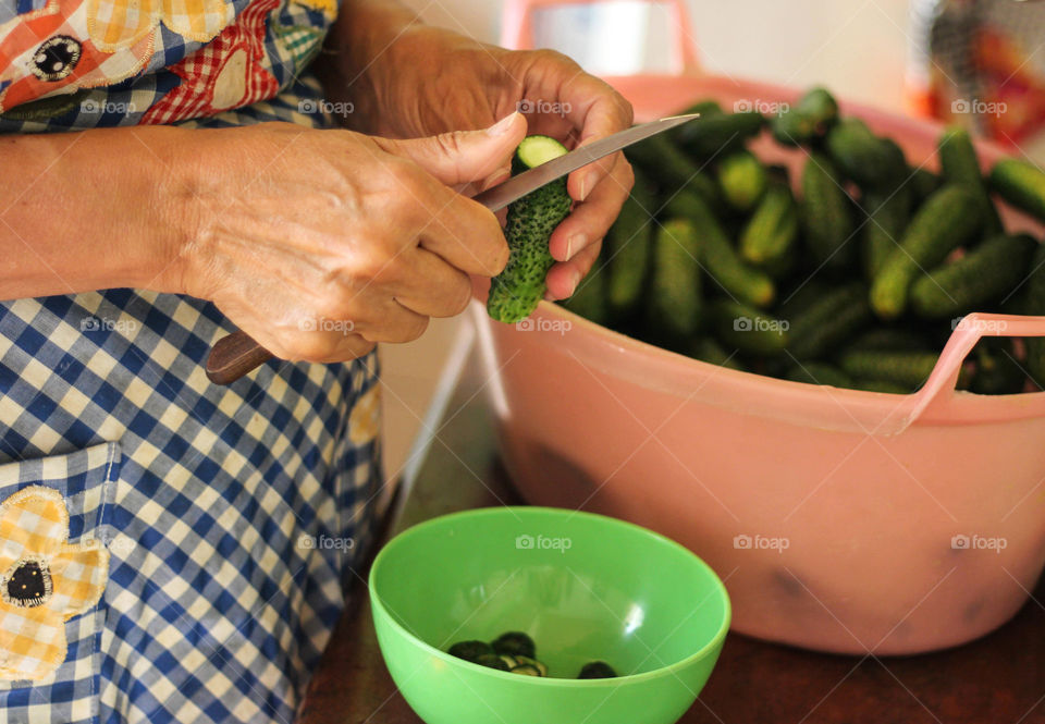 A woman cutting cucumbers with knife, preparing food for cooking