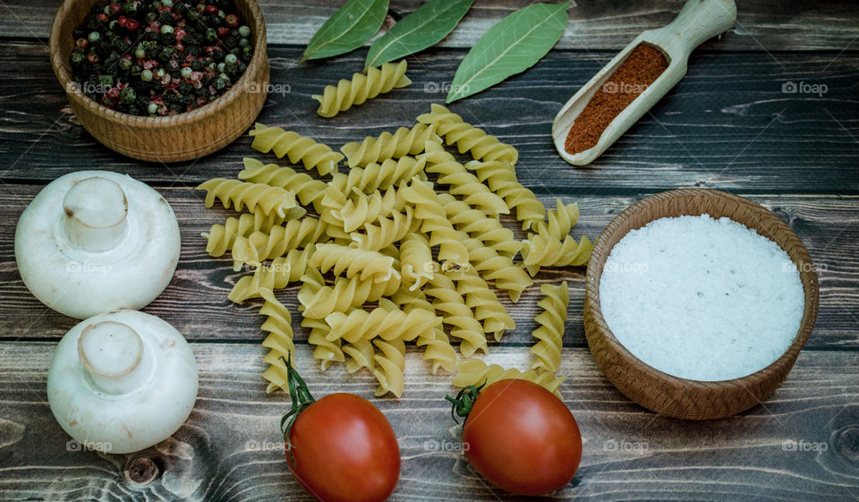 Raw pasta with ingredients and wooden accessories