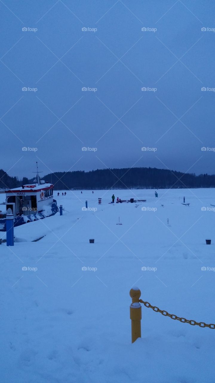 Snow blankets the ground on a mid winter afternoon of frozen Jyvaskyla lake in Finland.