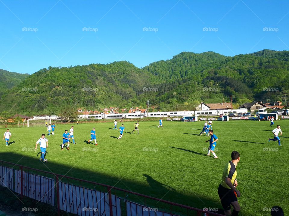 The train passes trough Nemila while a soccer match is in progress