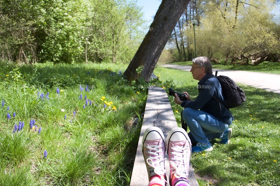 Mature man crouching on grass holding camera