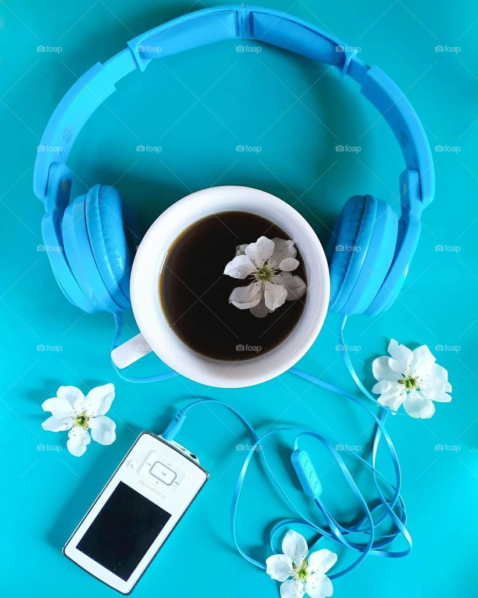 musical tea party, a cup of tea, headphones, flowers and good mood on a blue background
