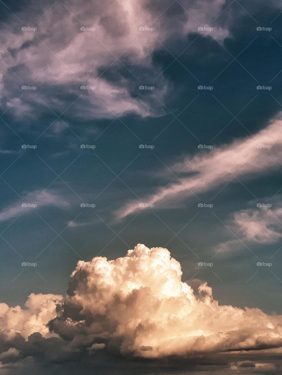 A new day presenting a dense and majestic cumulus of autumn clouds with orange and pinkish tones moving gently in the sky.