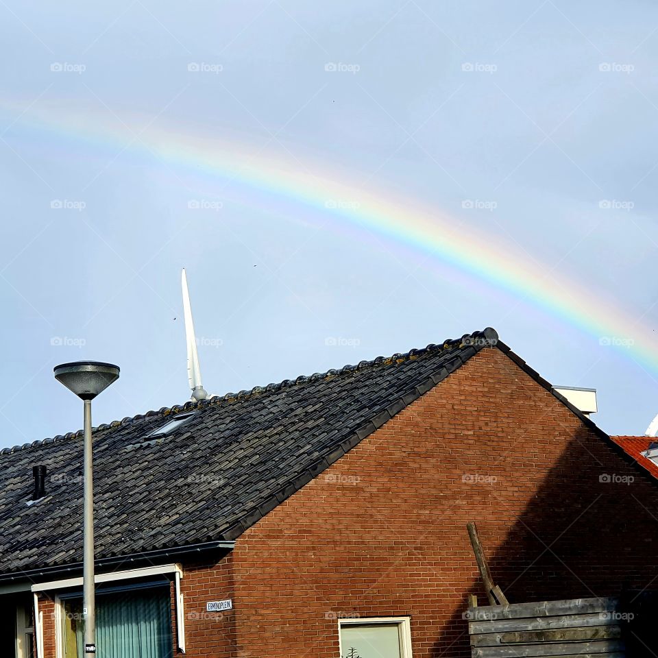Rainbow behind the houses high in the sky.
