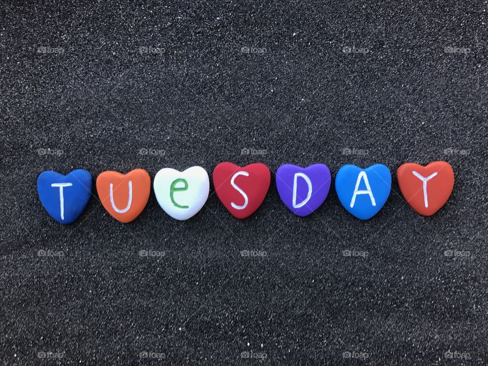 Tuesday, day of the week with multicolored heart stones over black volcanic sand 