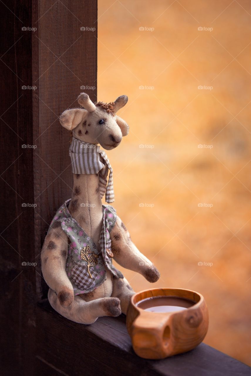 Toy giraffe with wooden mug of cocoa 