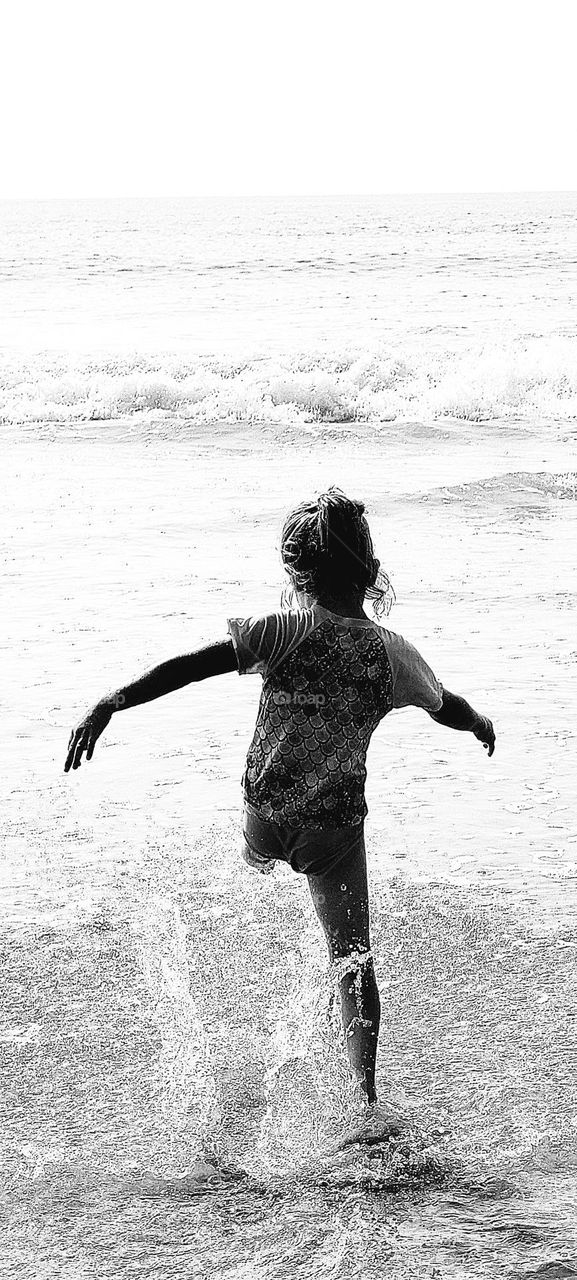 foap mission: young girl a child playing in the warm ocean waters of summer. splashing and playing in the ocean having fun