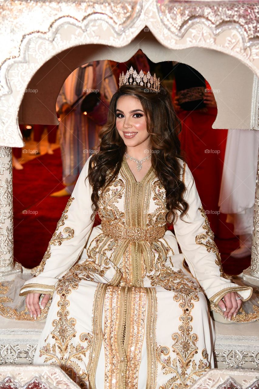 Moroccan bride waiting to enter wedding venue sitting on amaria