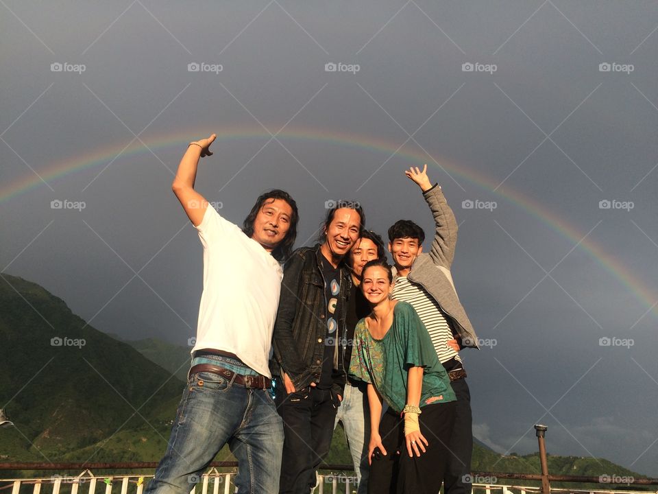 Portrait of happy friends against rainbow