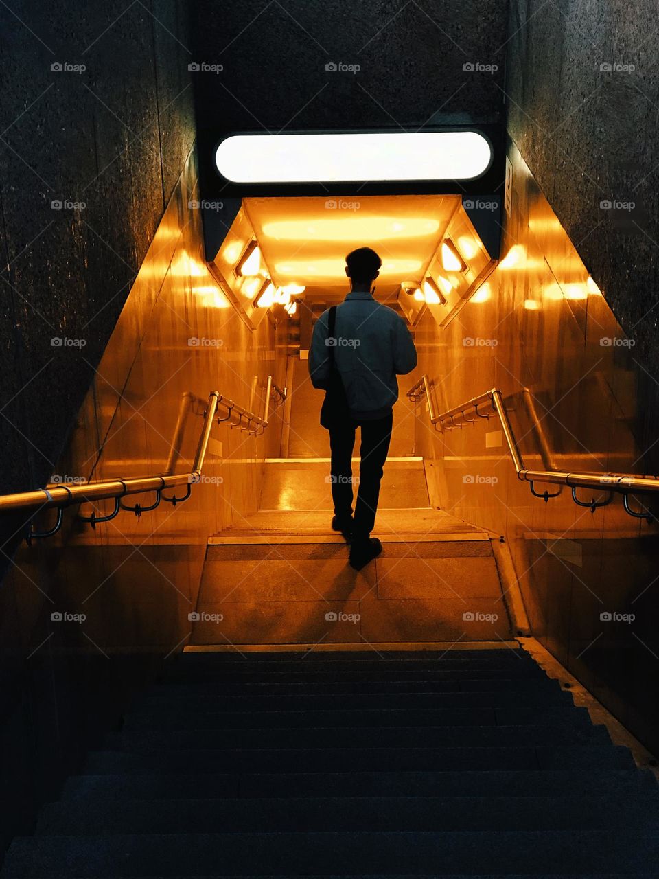 Unrecognisable man stumbles down stairs in subway, back view 