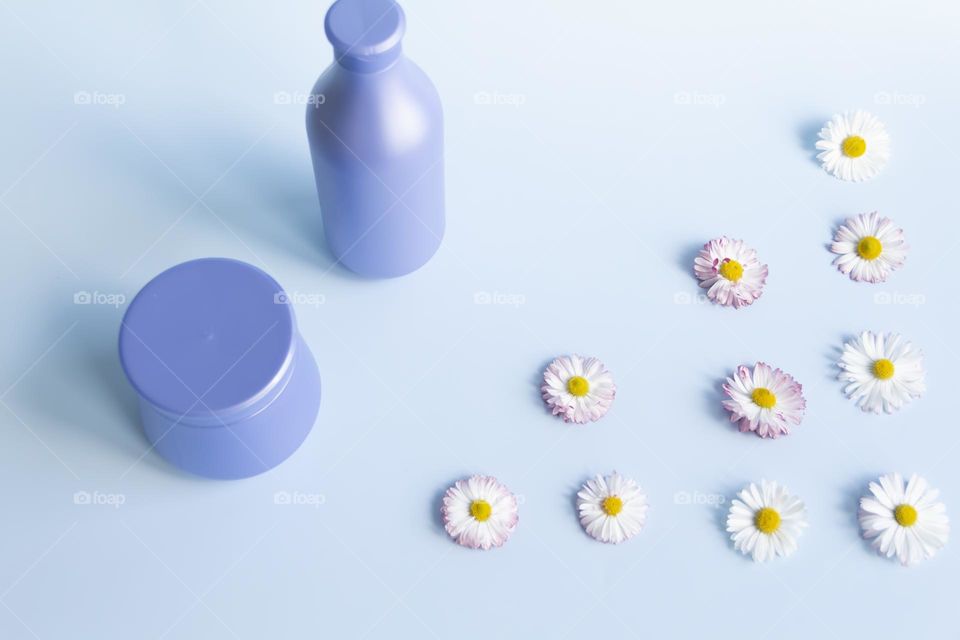 Jars with cosmetic products, beauty cosmetics in purple jars with fragrant flowers.