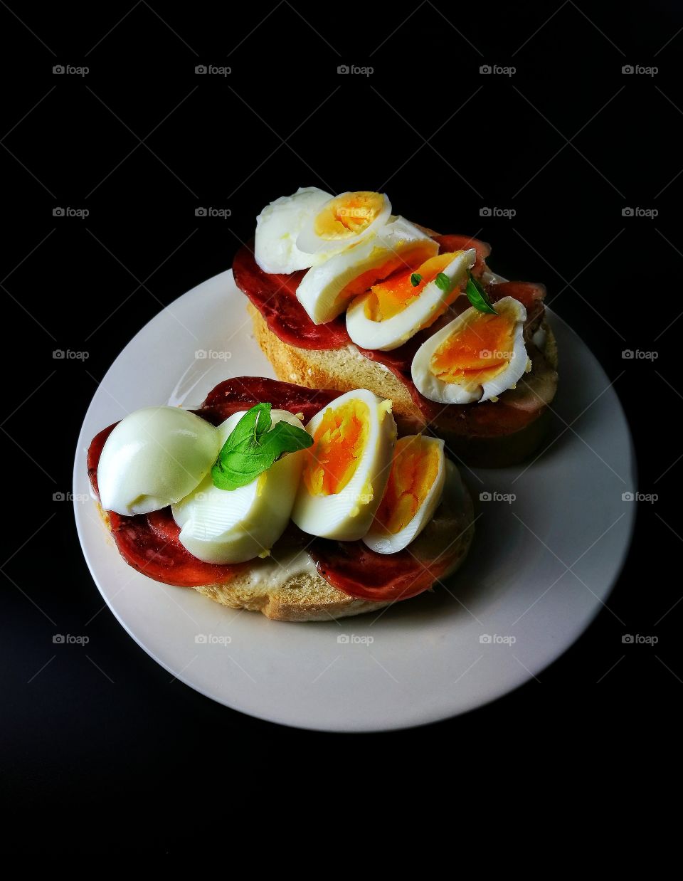 boiled eggs on bread and salami slices