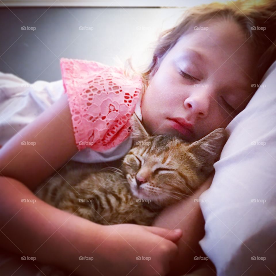 Little girl sleeping with her kitten 