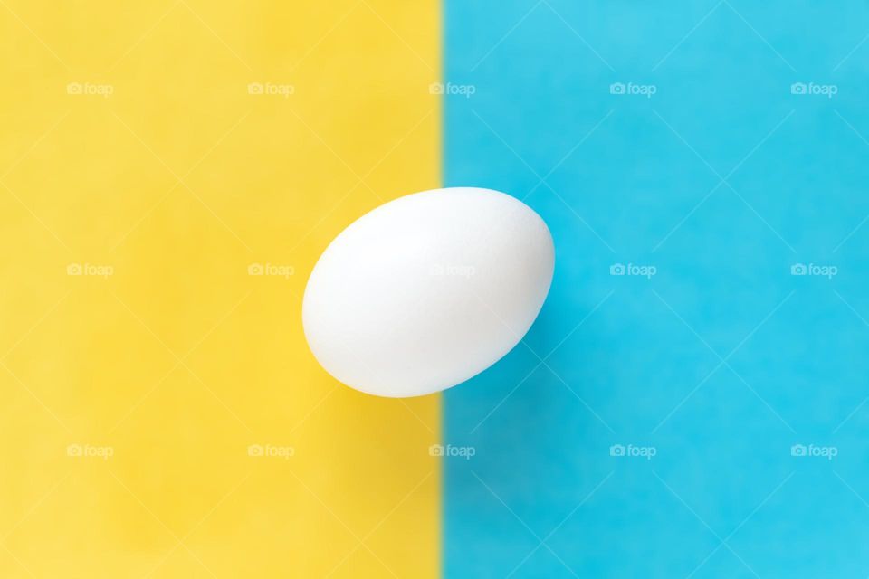 White egg on split yellow and blue background