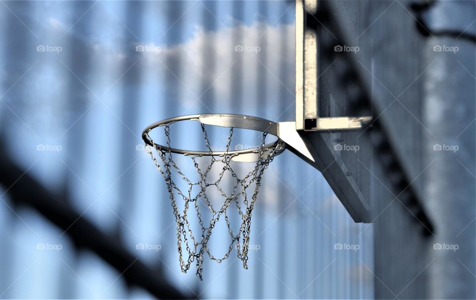 basket with metal net behind a metal fence with blue sky and grey clouds