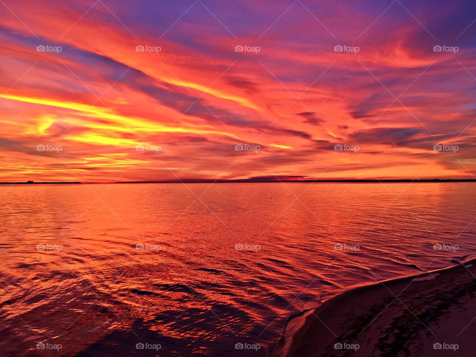 Sunrise, sunset and the moon -   It’s only me on the beach, allowing me to enjoy the sunset, undisturbed. The sun, a fiery orb, looks like it’s gradually receding into the waters below. Colors of red, orange, yellow and blue reflect off the surface