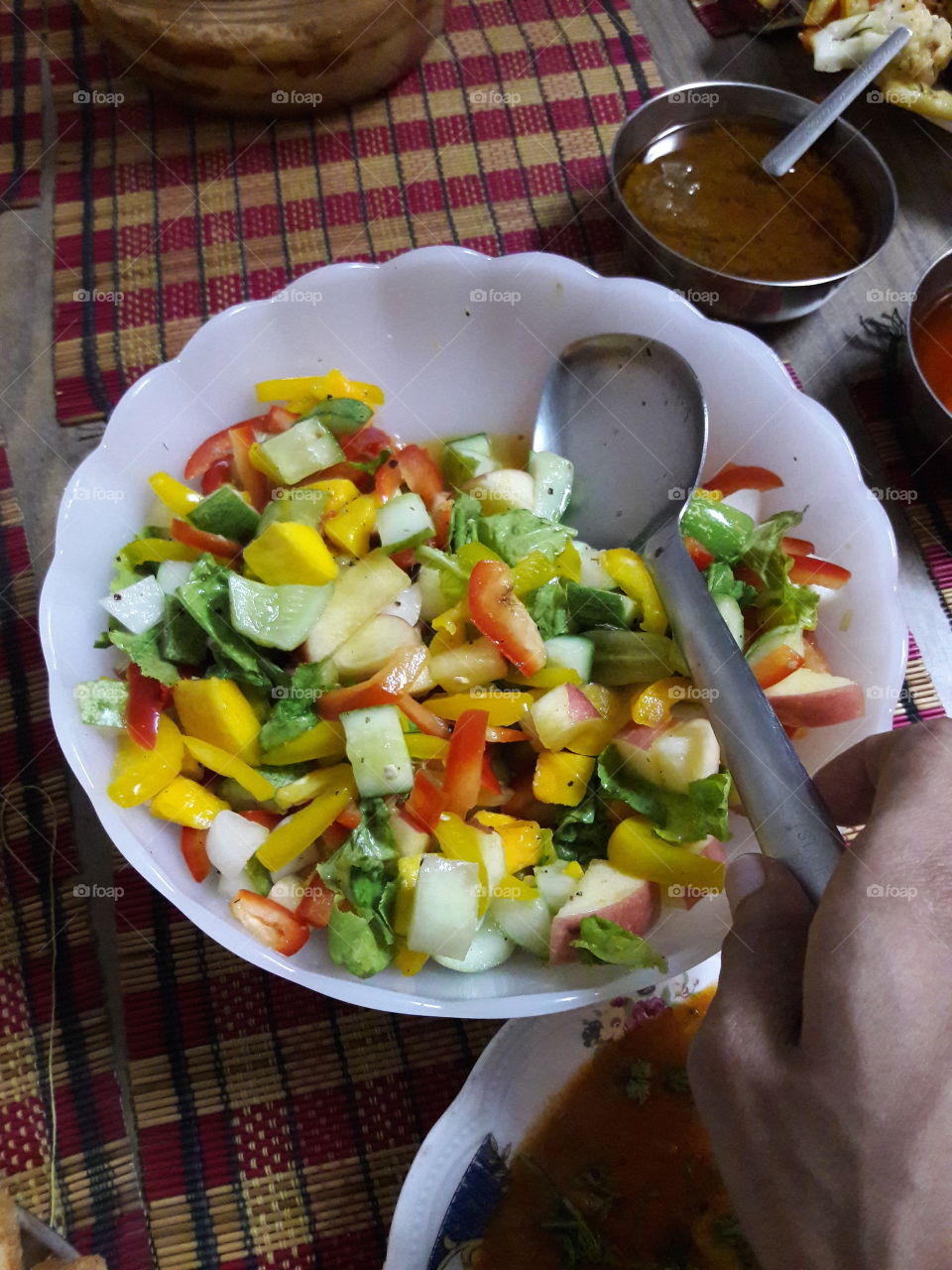 fresh multI colour vegetables as a vegetable salad with hand spoon and white container