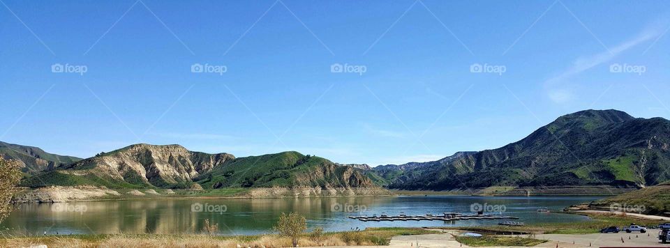 vista of a lake with hills in the background on a sunny day
