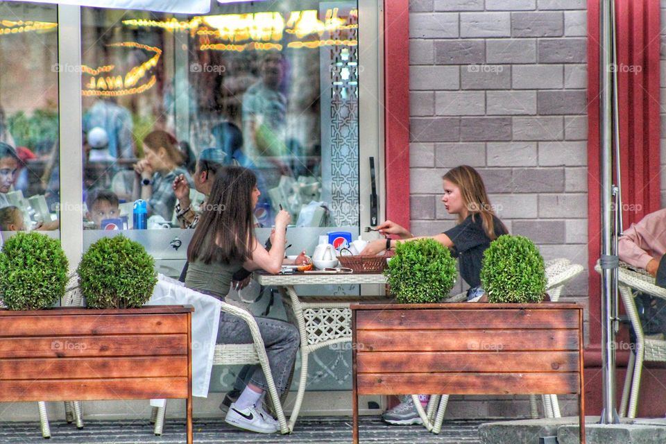 breakfast of two friends in a summer cafe next to the flower beds