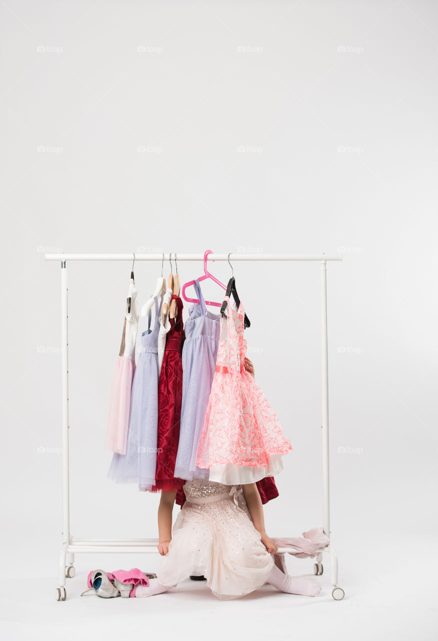 Two cute sisters is posing and playing with clothes and having fun.