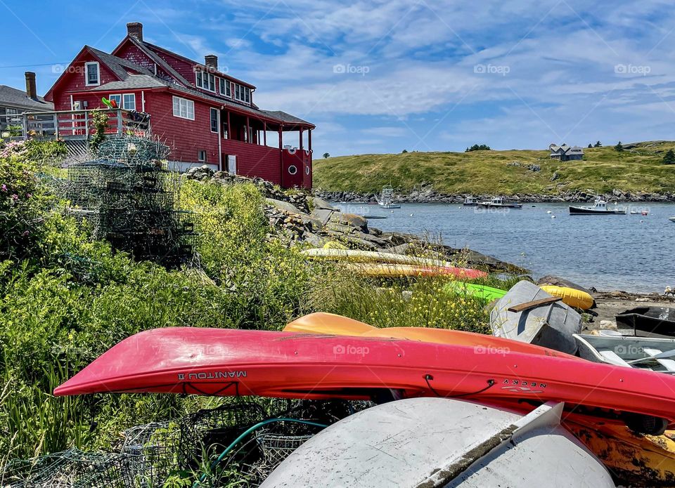 “Red Cottage at Swim Beach.”  Watercraft line the bank along the shore of Monhegan Island, Maine.