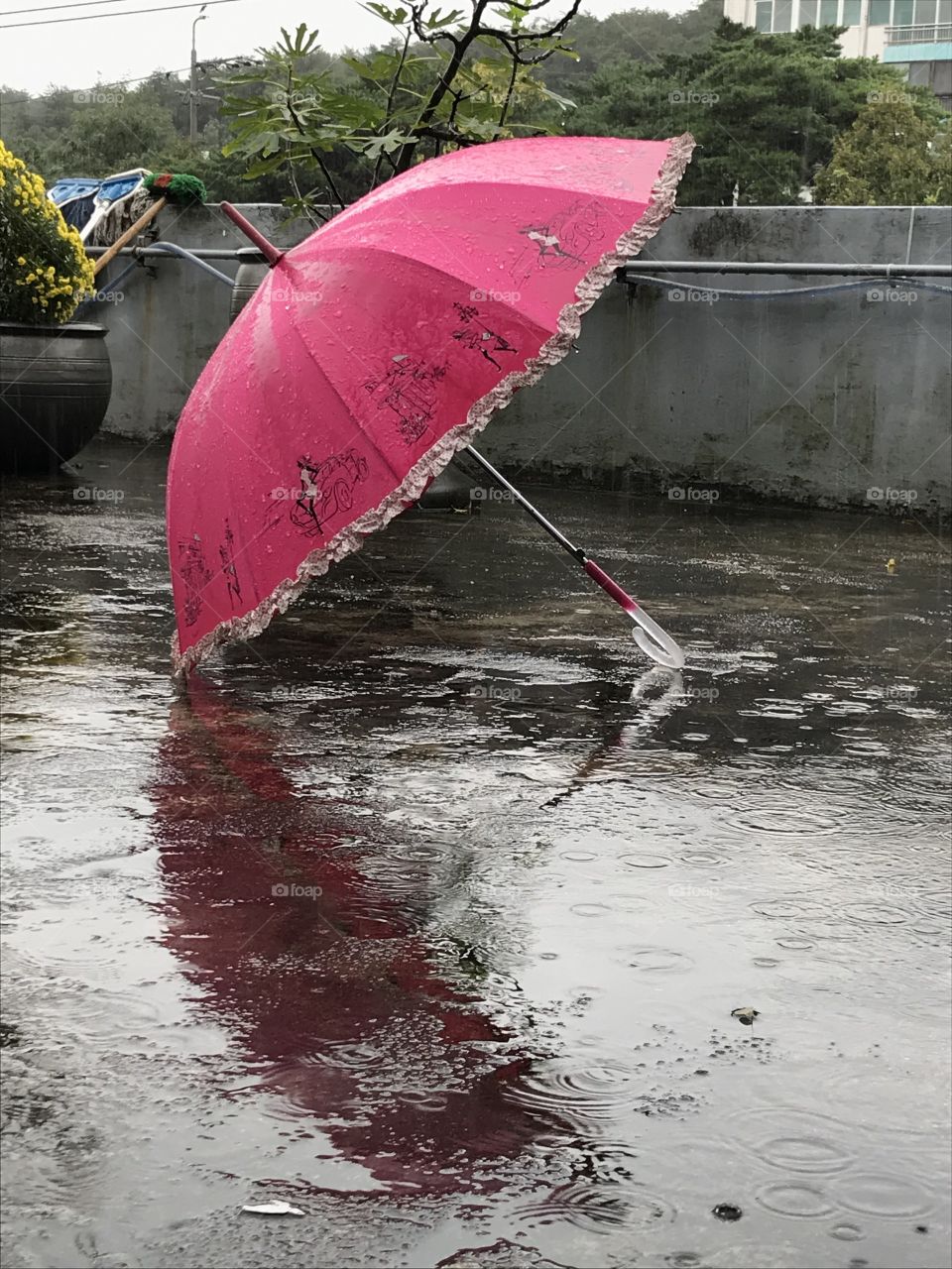 An pink umbrella under the heavy rain outside