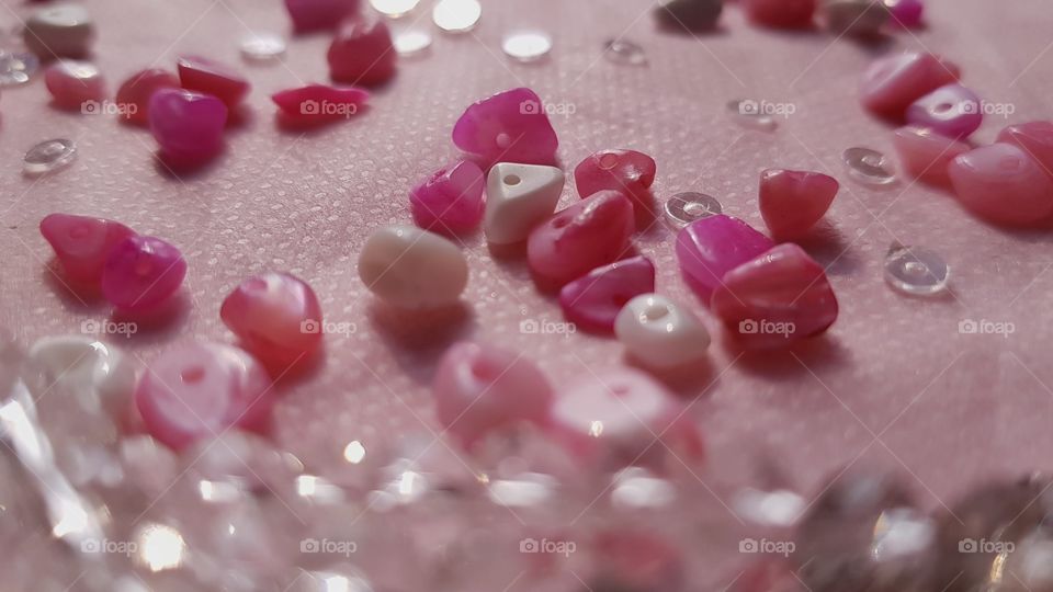 some pink marble stones scattered around all over the table with some gems..
