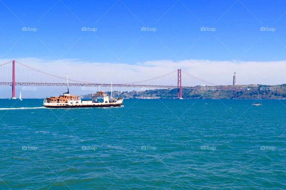 Ferry crossing the river and de 25 abril bridge in the background Portugal 