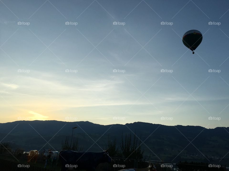 Hot air balloon over silhouetted mountain